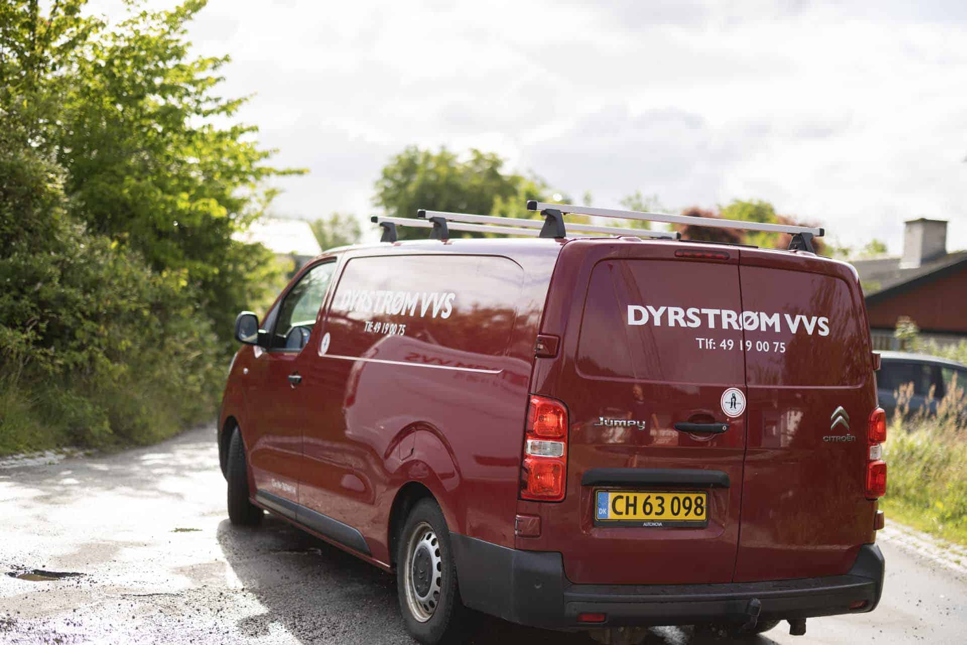 Side af rød firmabil med logo - "DYRSTRØM VVS Tlf 49 19 00 75"