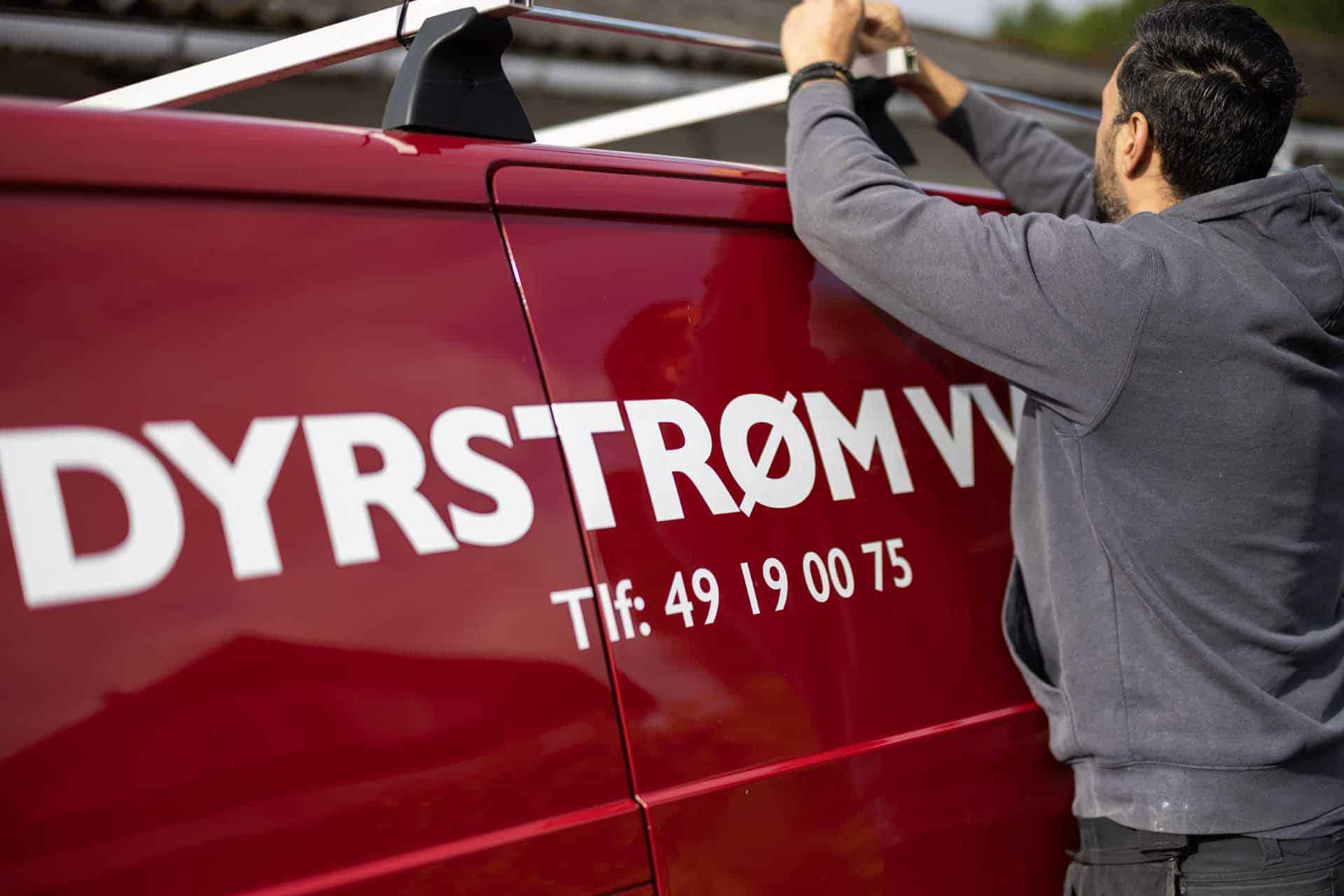 VVS-montør med materialer ved rød firmabil i Humlebæk