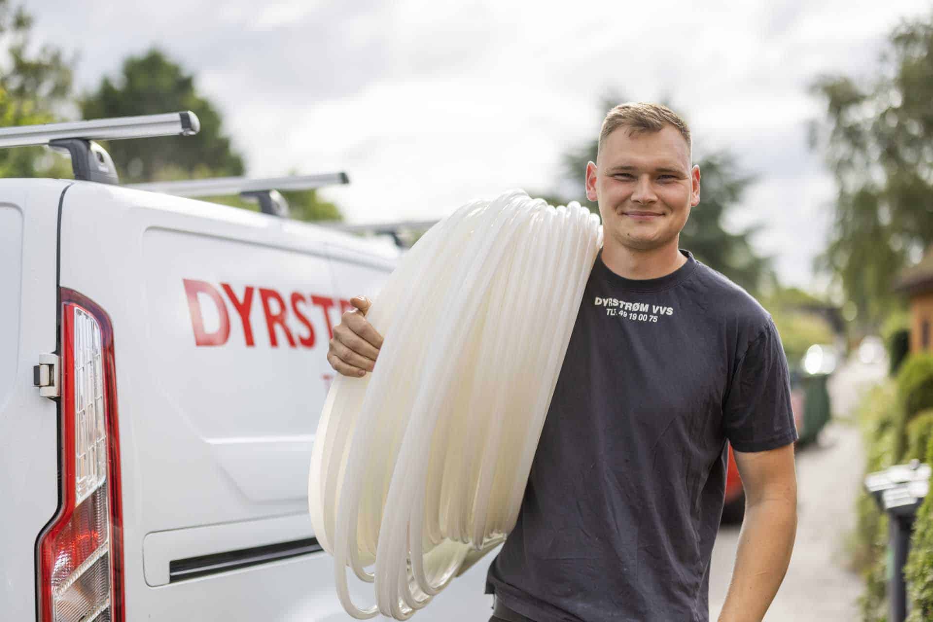 VVS-medarbejder fra Dyrstrøm VVS i Fredensborg bærer ruller med hvide rør - "DYRSTRØM VVS"